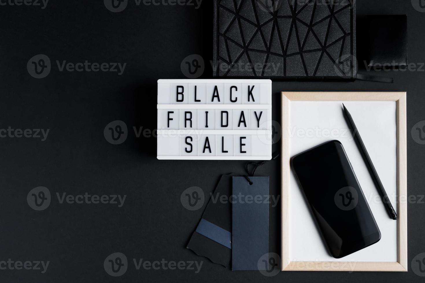 Black Friday online sale concept. Monochromatic flatlay on dark background. Smartphone and accessories. photo
