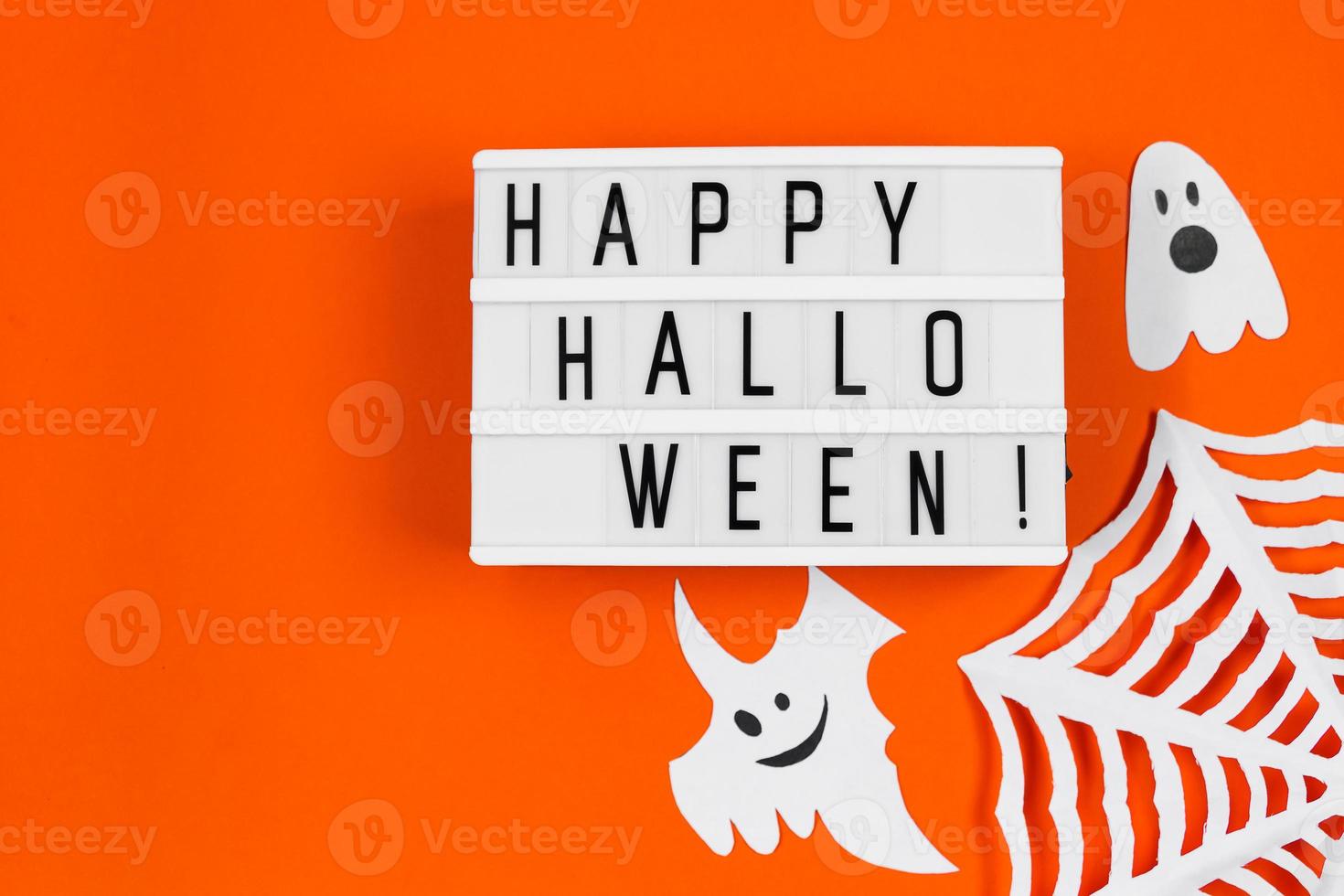 Halloween concept. Festive decorations - paper ghosts and spider web on orange background. photo