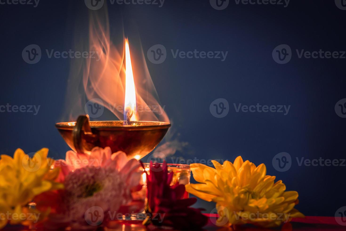 Happy Diwali. Burning diya oil lamps and flowers on blue background. Traditional Indian festival of light. photo