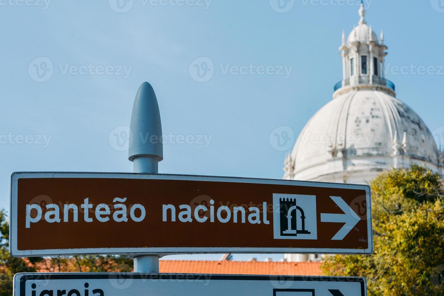 Outside facade of the National Pantheon, a 17th-century monument of Lisbon, Portugal against a blue sky with sign pointing towards its entrance photo