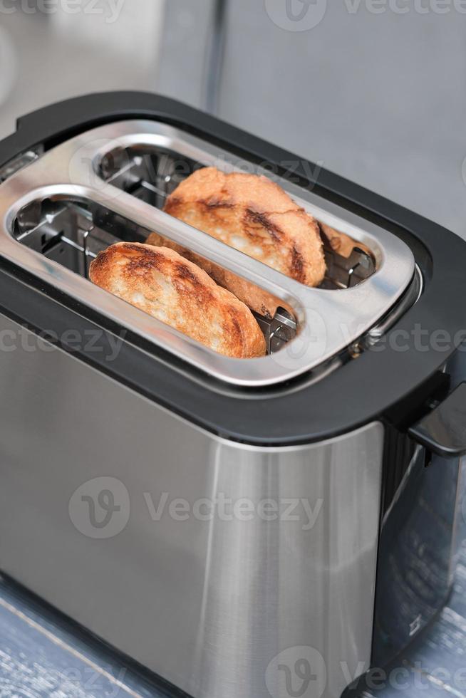 two slices of bread in toaster. ready toasts for breakfast. kitchen supply for cooking. photo