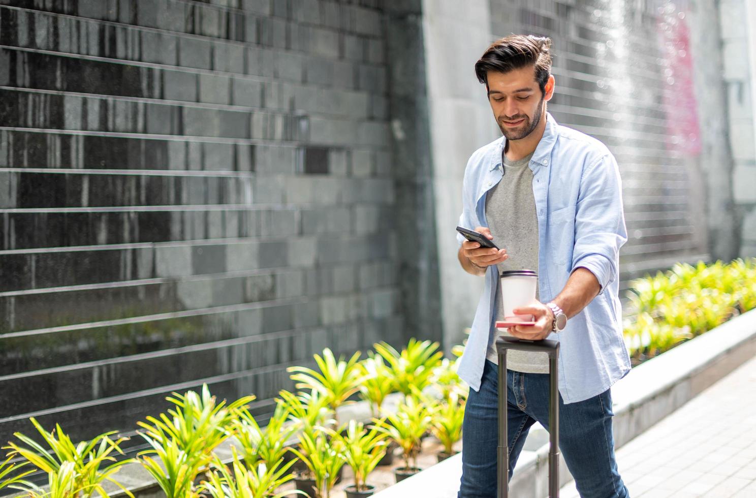 Young caucasian holding phone, and taking photo of coffee cup, bag, and walk in city street.