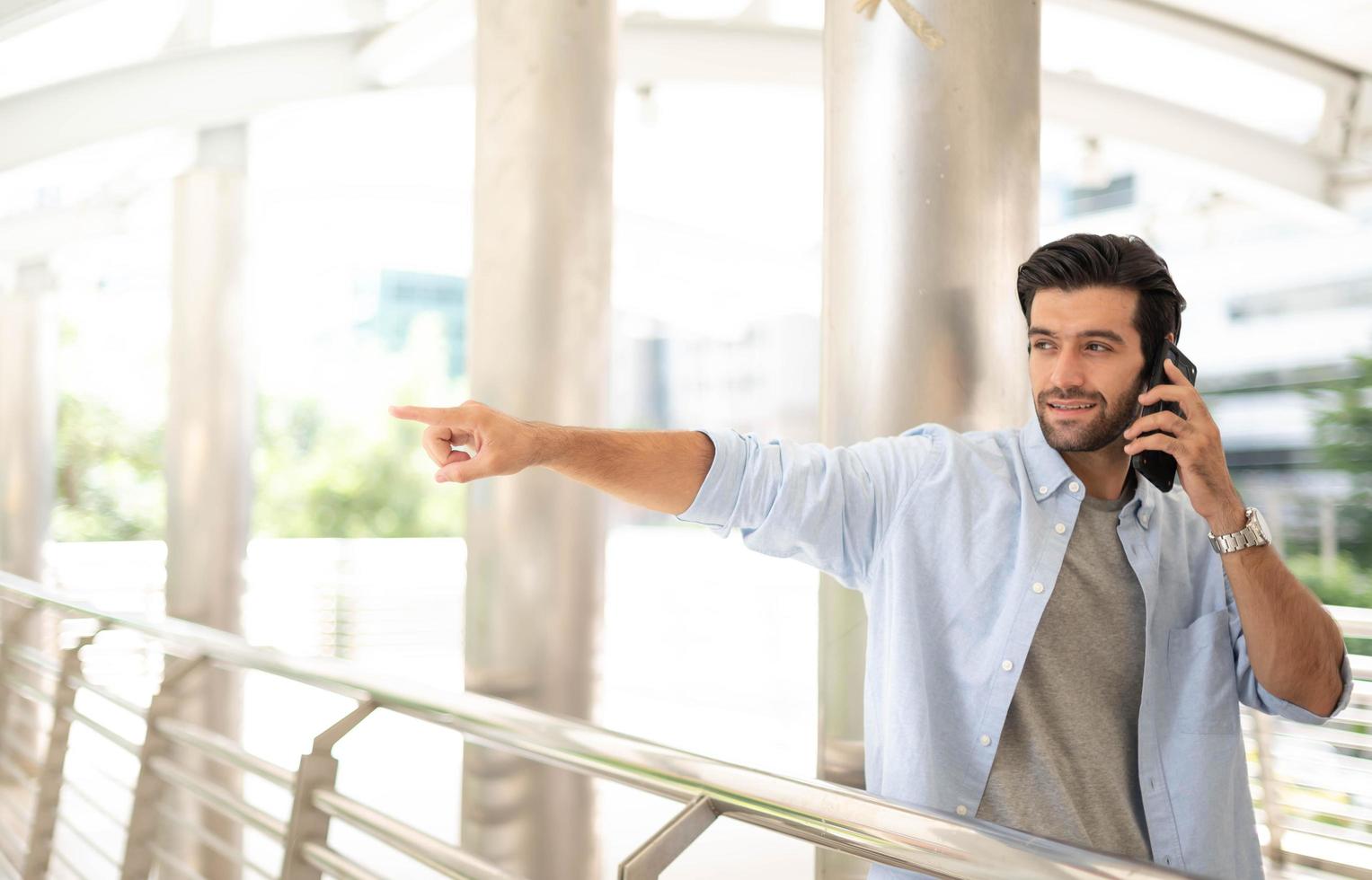 inessman pointing to something while using a smartphone to talk with his friend at the outdoor photo