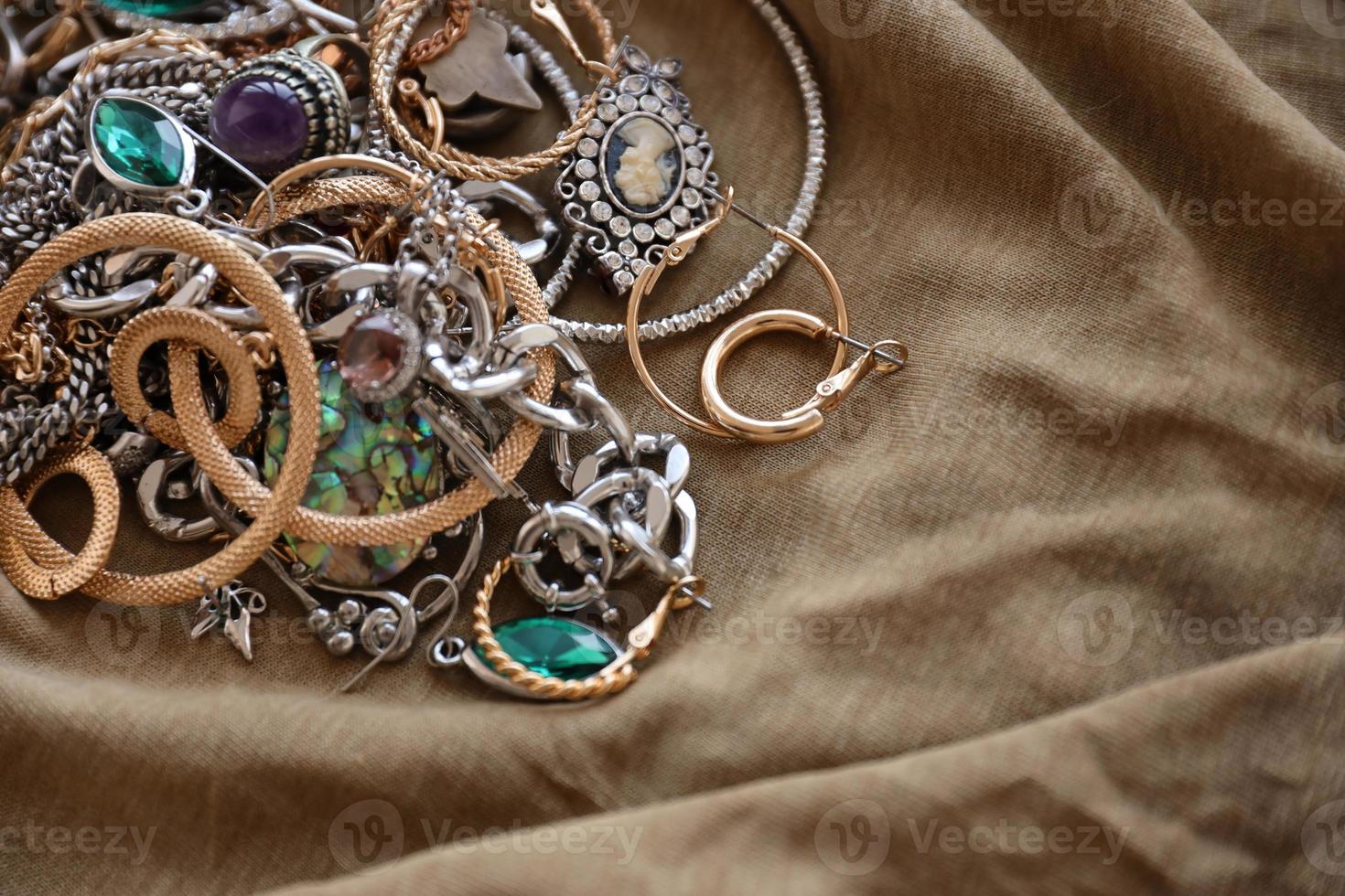 Bunch of stolen jewelry on military uniform cloth fabric. Looting by Russian soldiers in the Ukrainian cities during the Russian attack on Ukraine. Marauders and looters photo