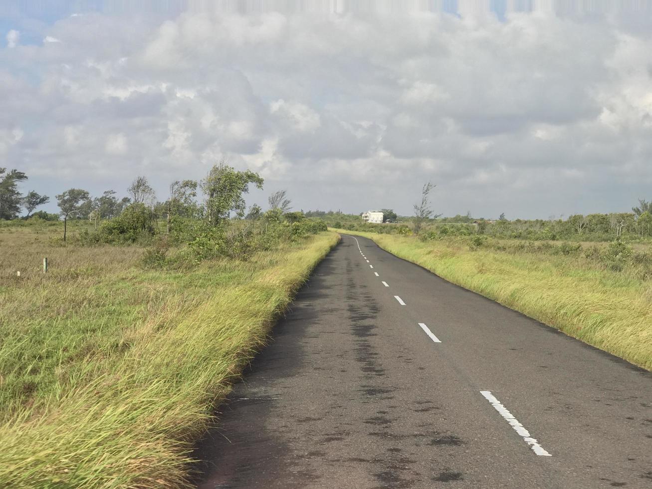 The view of the highway with beautiful grass stretching along the edge of the road and white clouds covering photo