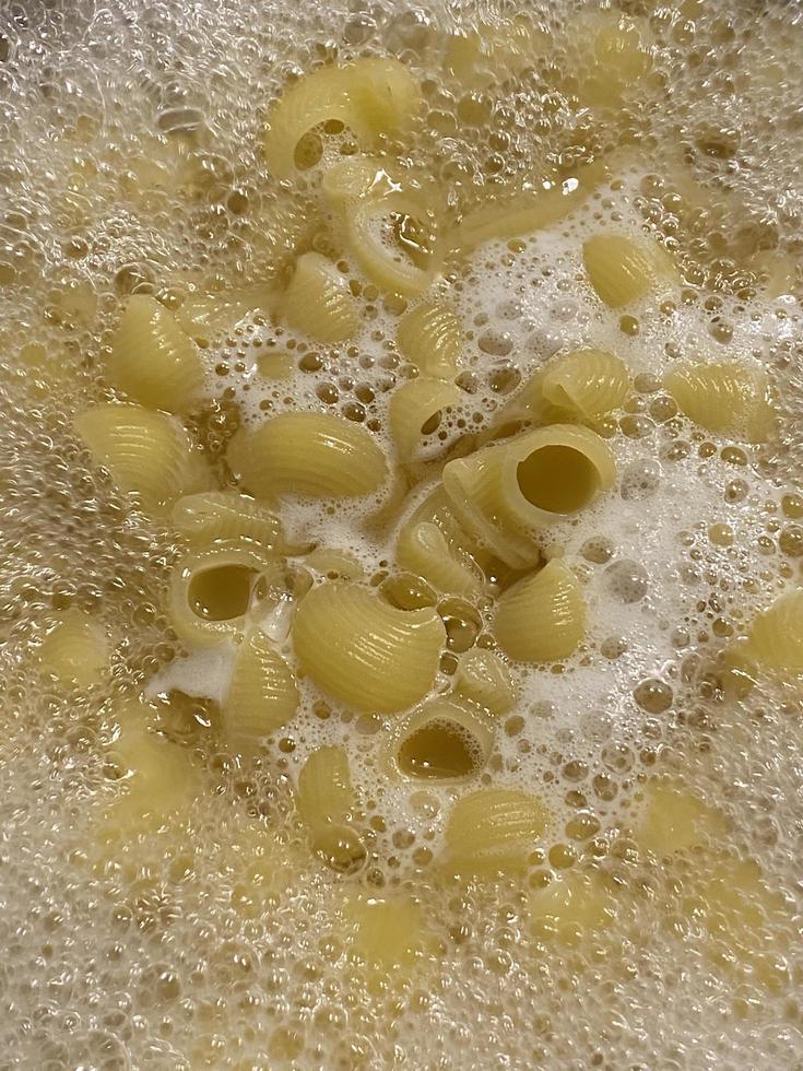 Cooking pasta in a pot. Boiling water and food ladle. Close-up. photo