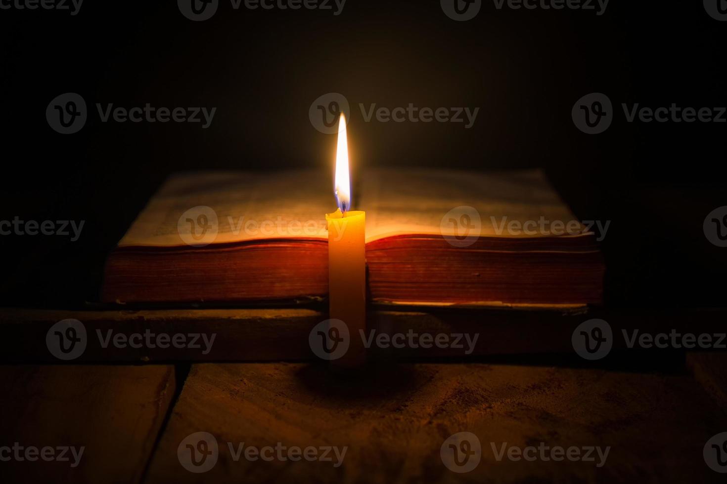 Light candle with holy bible and cross or crucifix on old wooden background in church.Candlelight and open book on vintage wood table christianity study and reading in home.Concept of christ religion photo