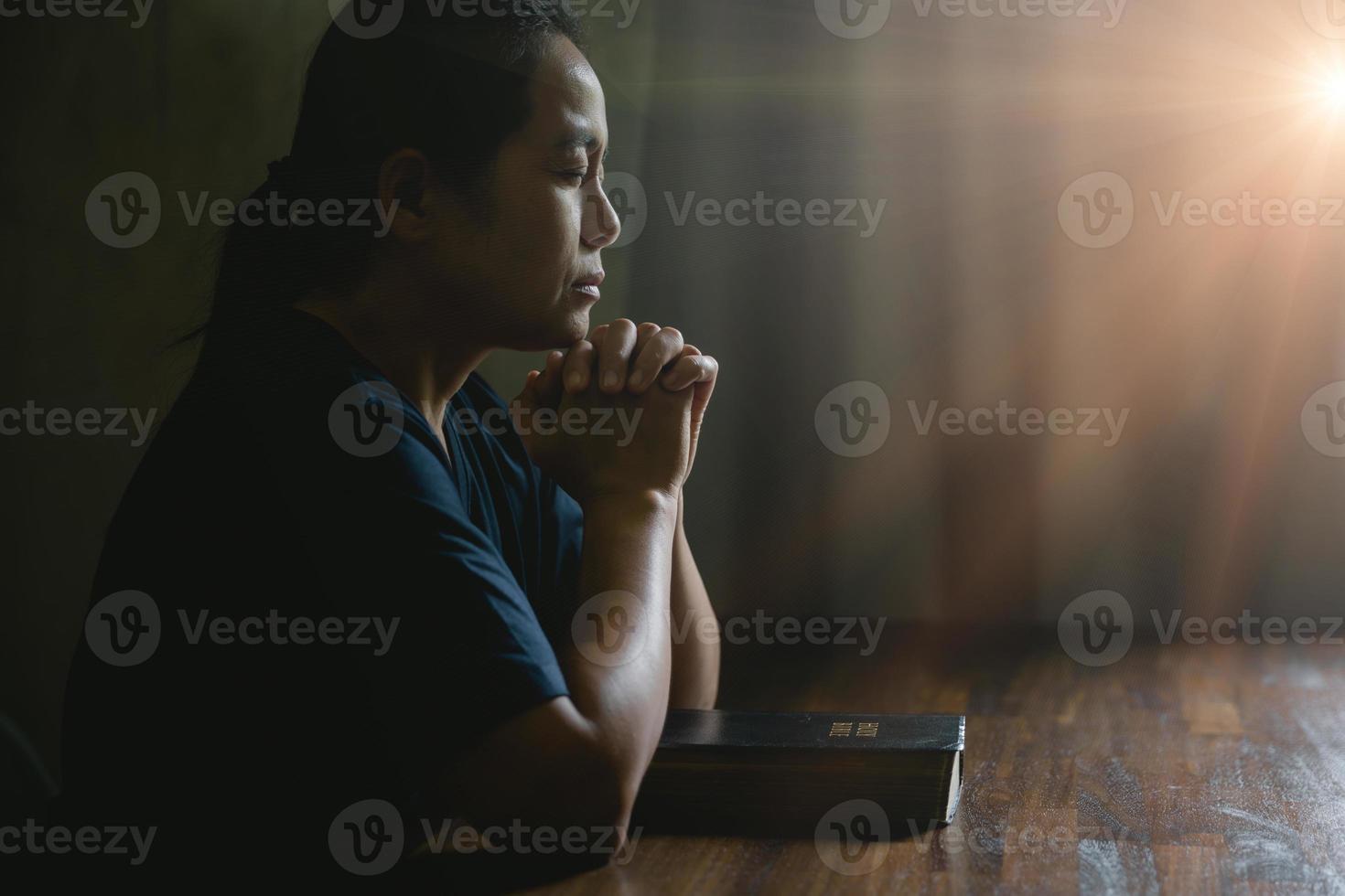 mano de persona de oración en fondo negro. la mujer católica cristiana está rezando a dios en la oscuridad en la iglesia. chica cree y fe en jesucristo. la religión de cristo y el cristianismo adoran o rezan concepto. foto