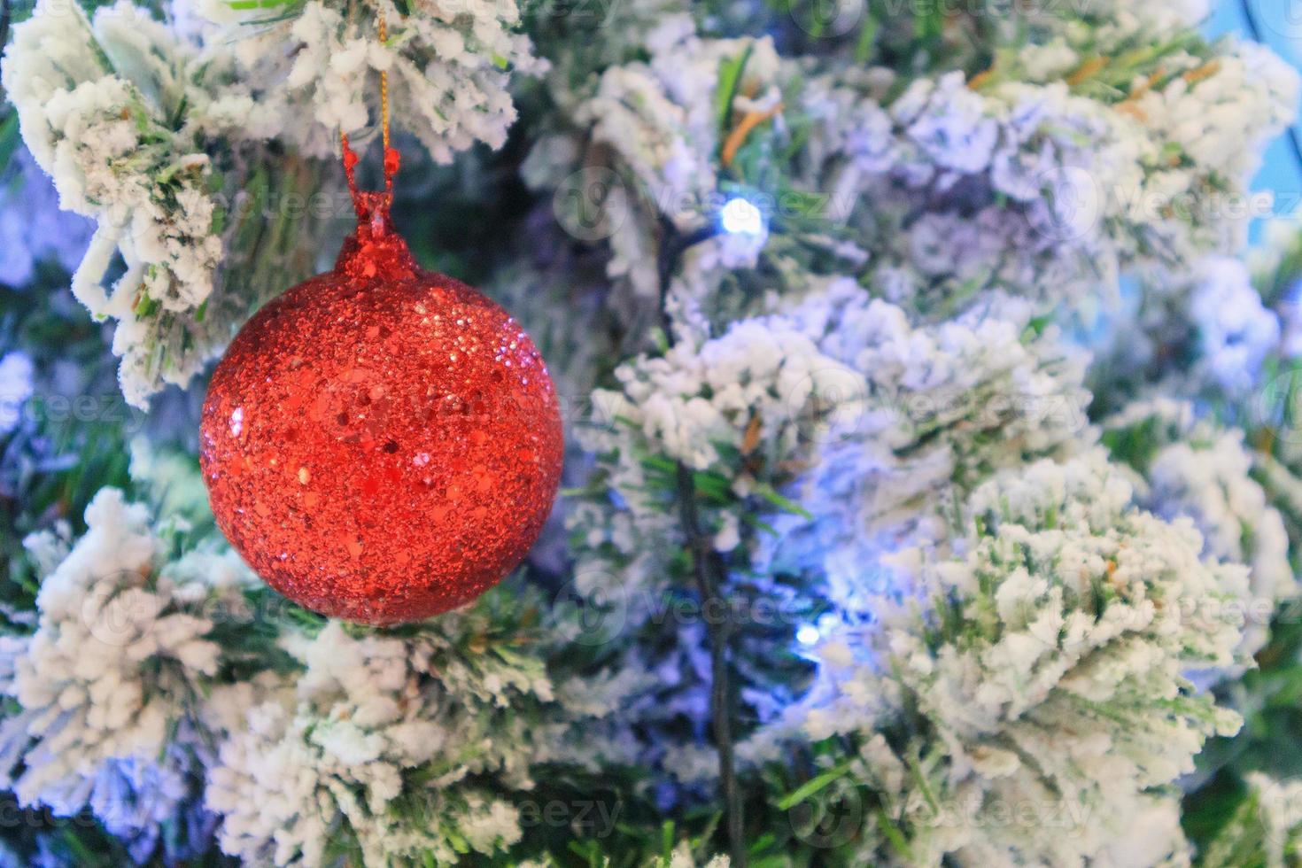 Christmas tree decorated with red ball on pine branches background photo