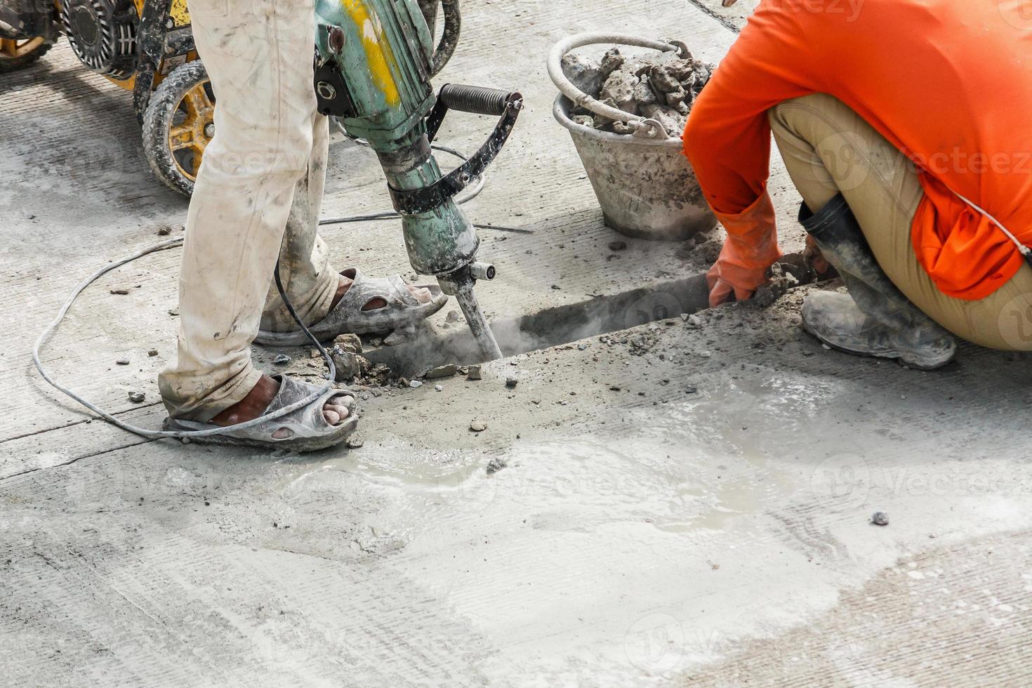 Construction worker using jackhammer drilling concrete surface photo