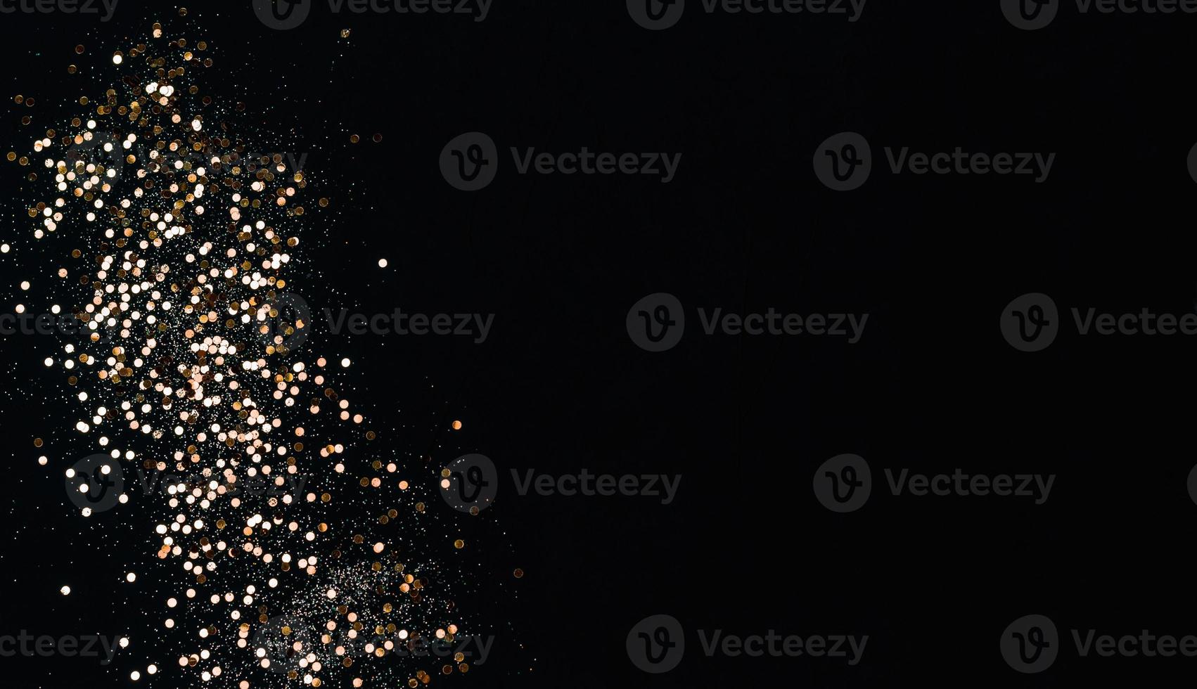 Golden confetti and sparkles on black background. Top view, copy space. photo