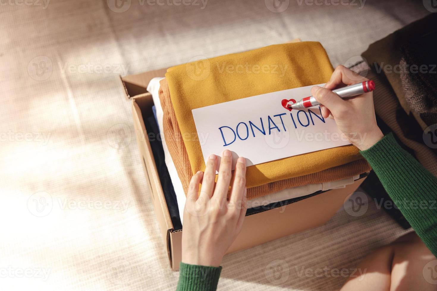 Clothes Donation Concept. Box of Cloth with Donate label. Woman Preparing Used Old Garment at Home. Top View photo
