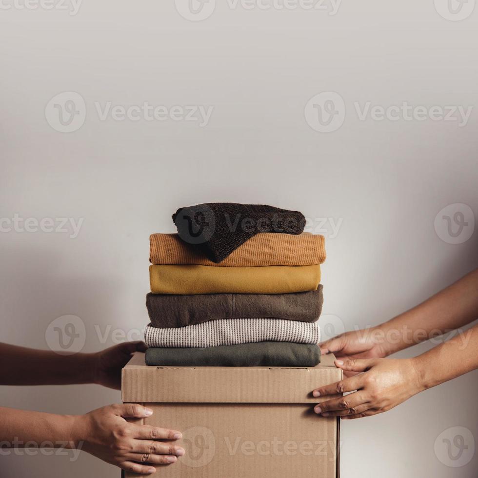 Donation Concept. The Volunteer Giving a Donate Box with a Full of Clothes to the Recipient. photo
