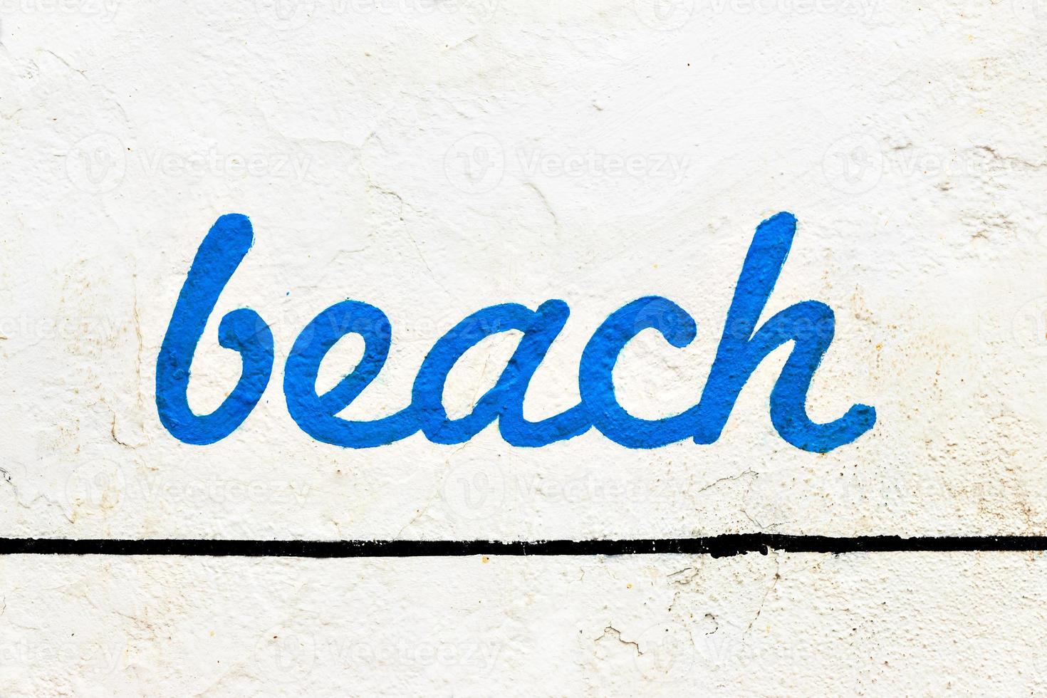 Blue beach sign painted on a white wall. Horizontal image. photo