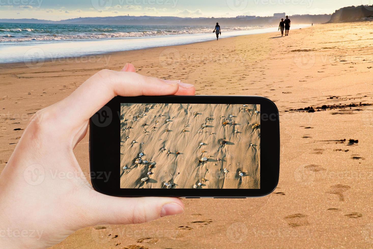 tourist taking photo of sand beach close up