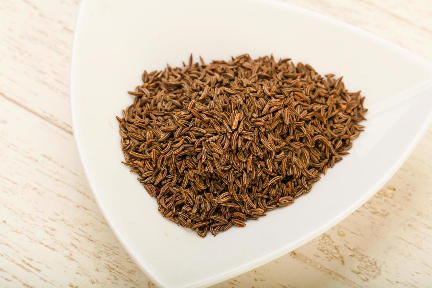 Caraway pile in a bowl on wooden background photo
