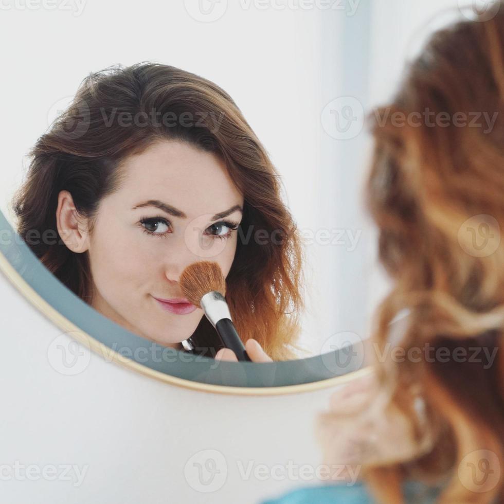mirror portrait of a young woman powdering her nose photo