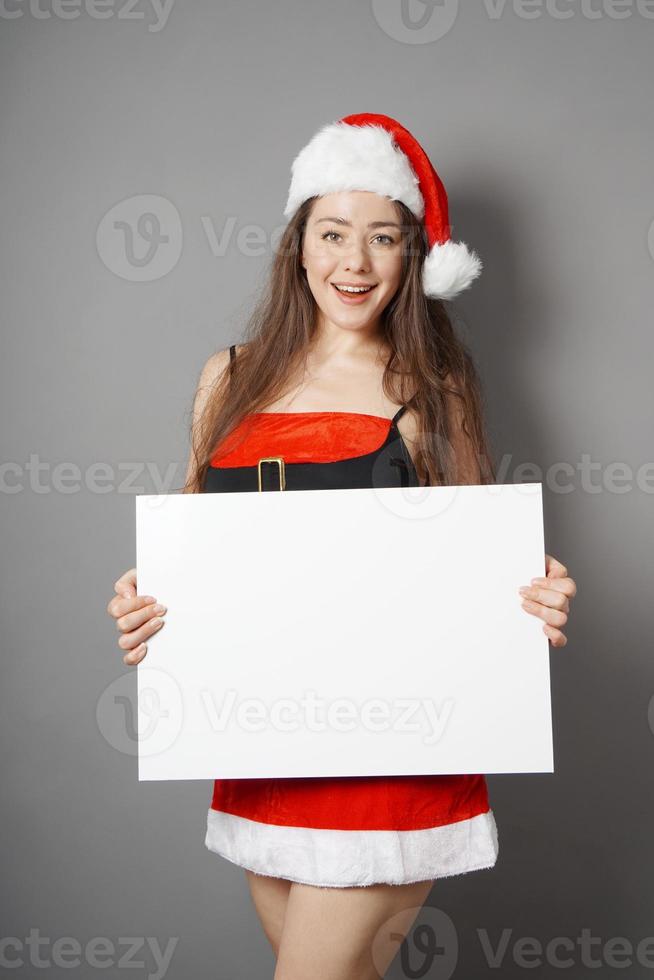 miss santa presentando un cartel en blanco con espacio de copia foto