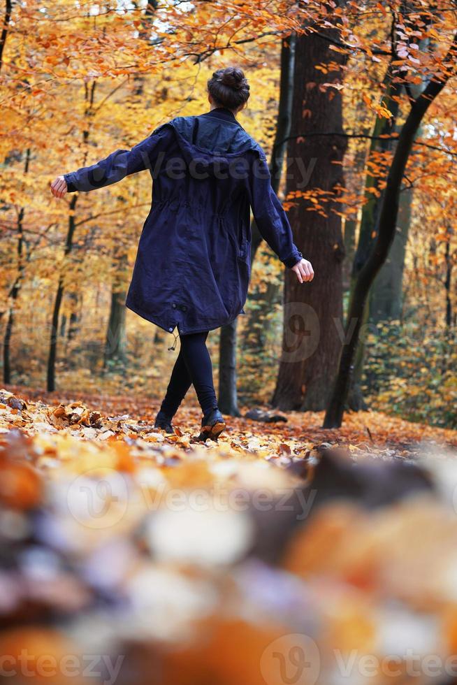 rear view of woman enjoying autumn walk in forest photo