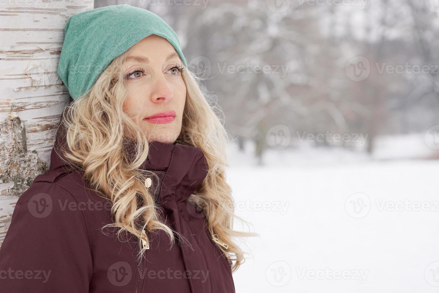 woman leaning against tree in winter photo