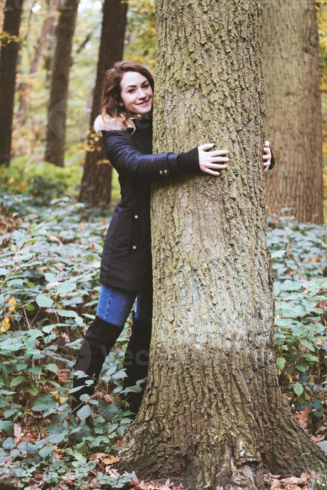 Young woman hugging a tree in forest- nature lover and tree hugger photo