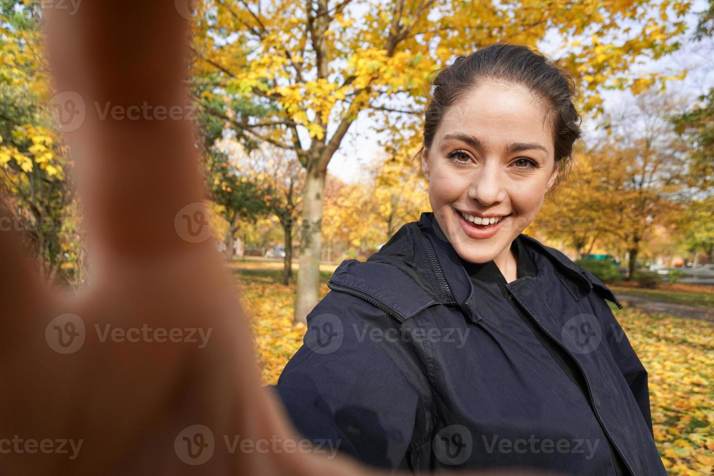 happy young woman taking selfie photo in park with autumn colors
