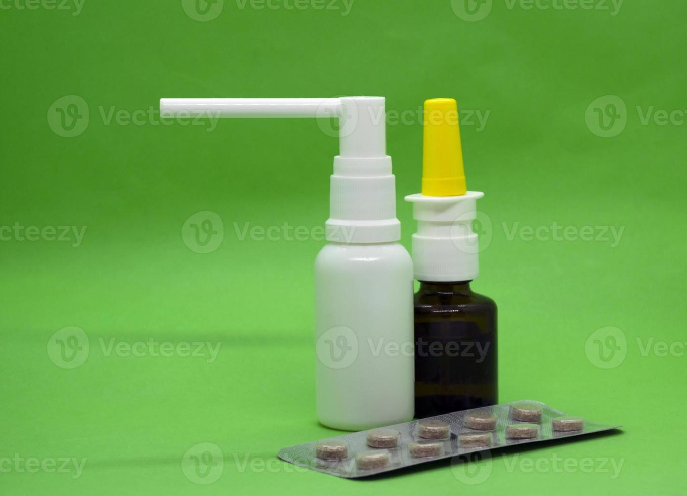 Throat spray, pills and nasal drops on a green background photo