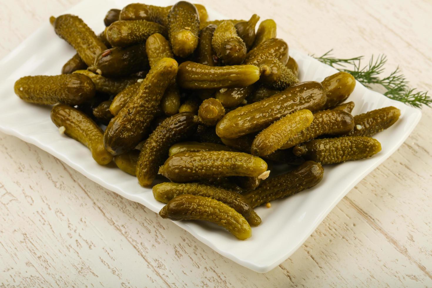 Picled cucumbers on the plate and wooden background photo