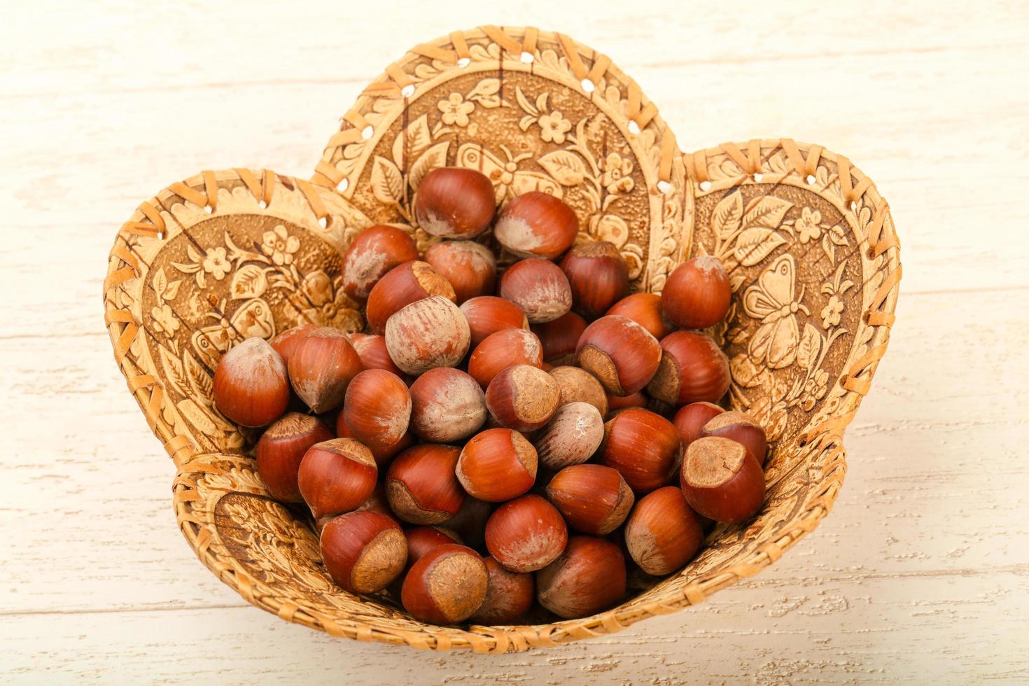 Hazelnut heap in a basket on wooden background photo