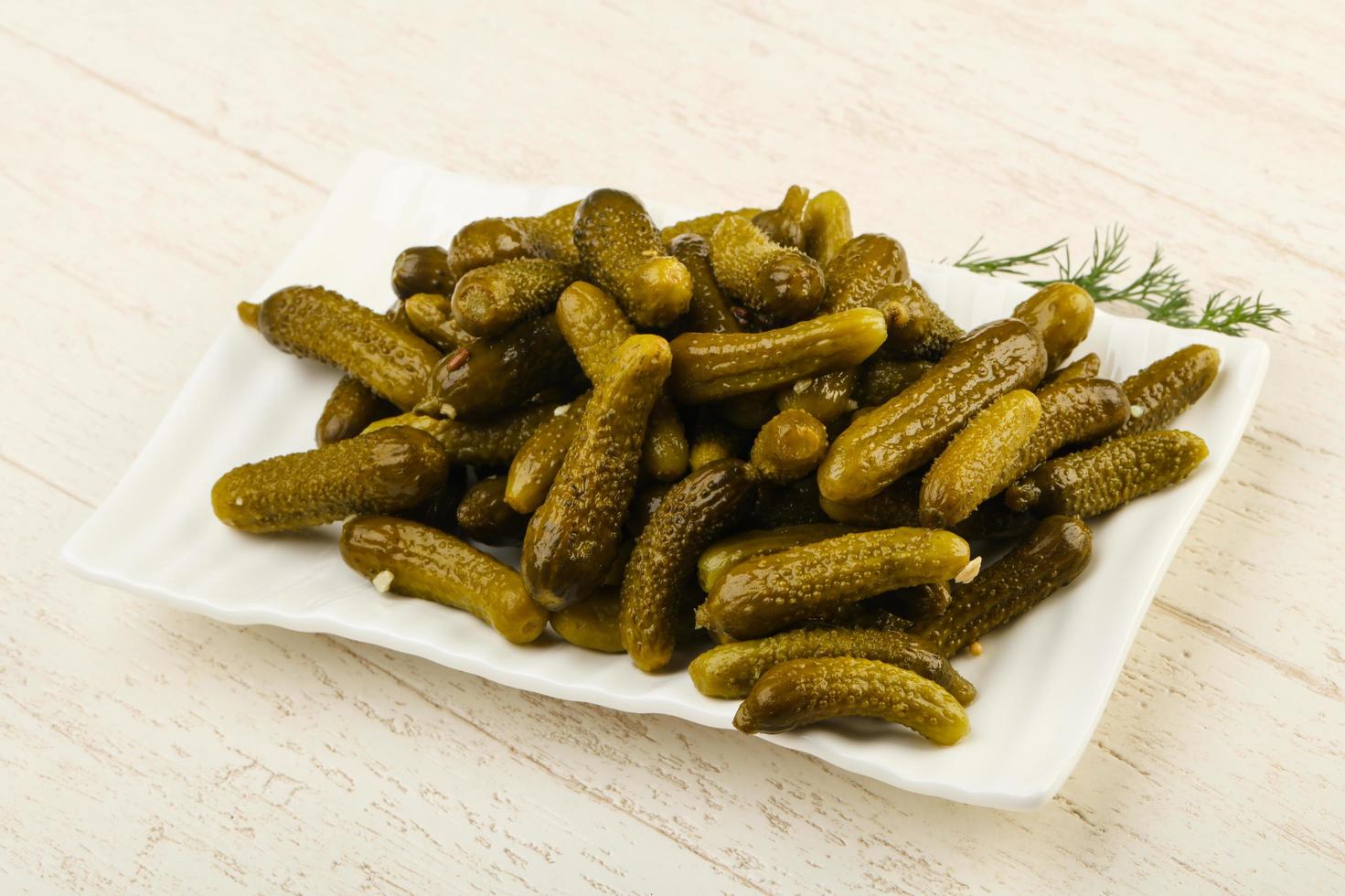 Picled cucumbers on the plate and wooden background photo