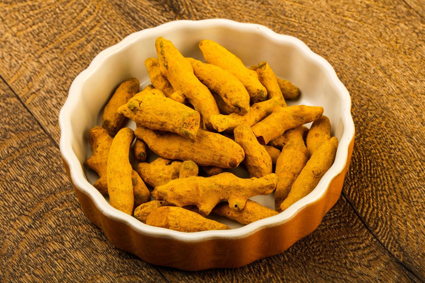 Tumeric roots in a bowl on wooden background photo