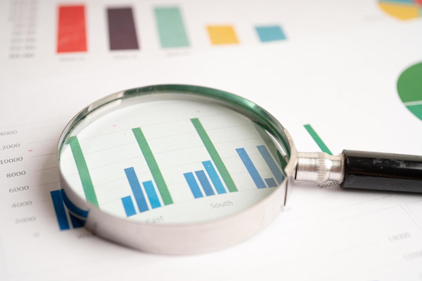 Magnifying glass on chart graph spreadsheet paper. Financial development, Banking Account, Statistics, economy, Stock exchange trading, Business office company meeting concept. photo