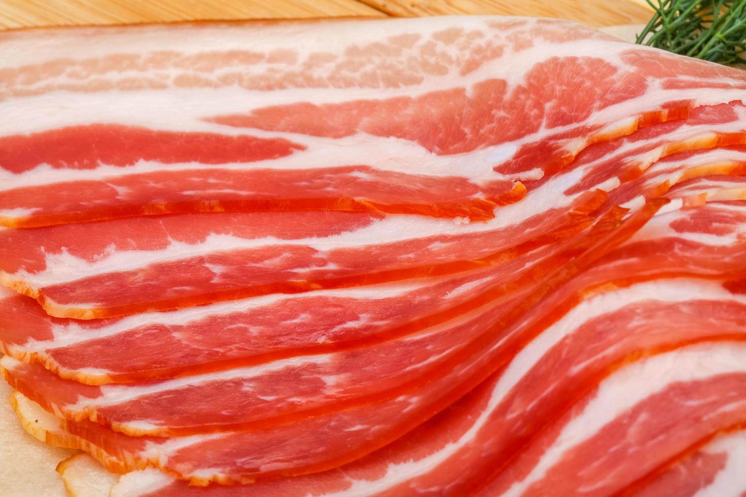 Sliced bacon on wooden board close up view photo