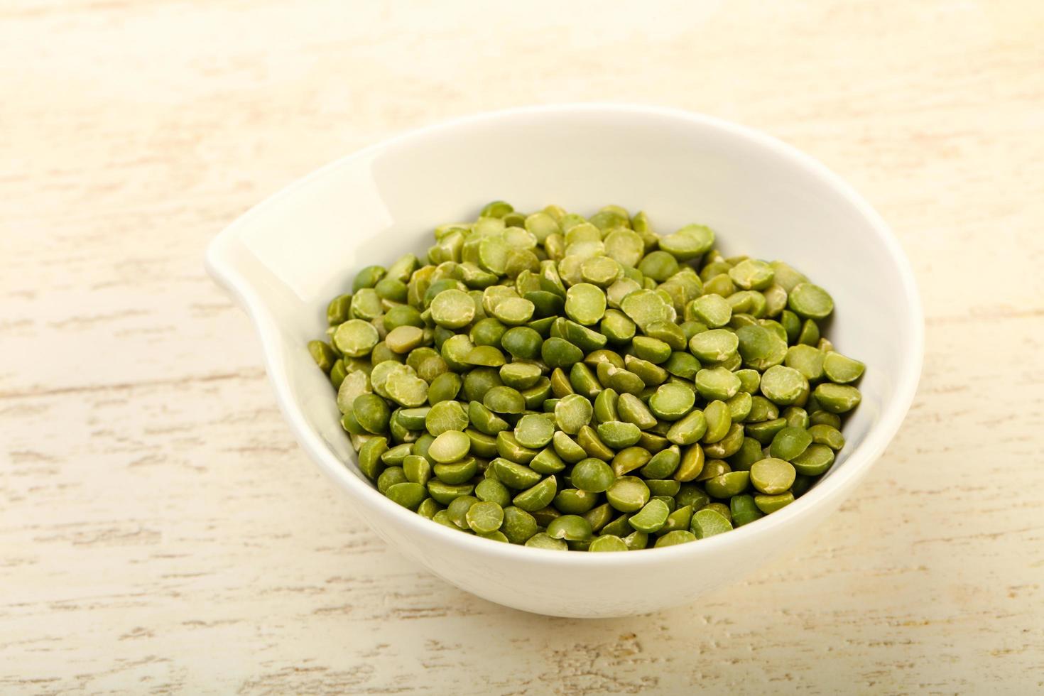 Green peas in a bowl on wooden background photo