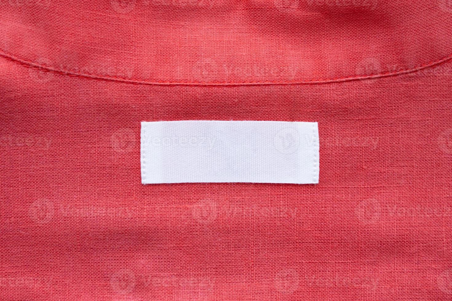 White blank clothing tag label on red linen shirt fabric texture background photo