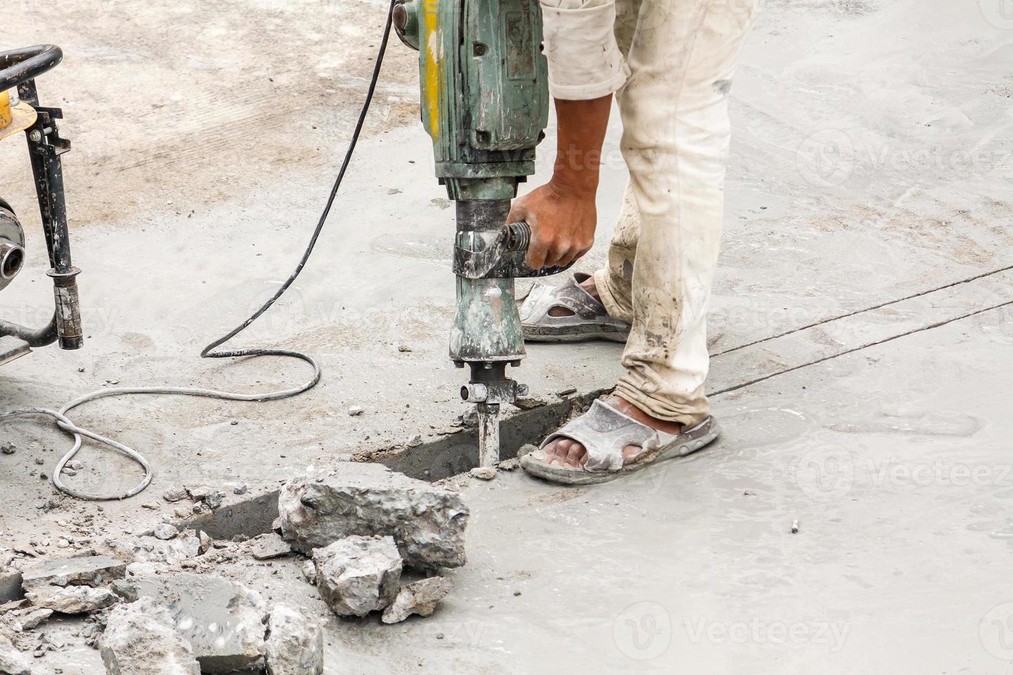 Construction worker using jackhammer drilling concrete surface photo