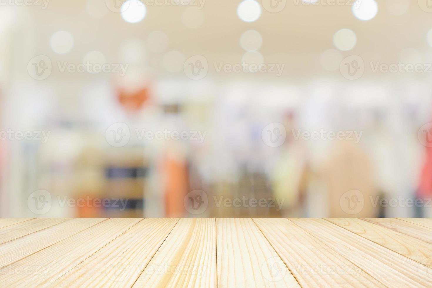 Empty wood table top with modern clothing store interior blur abstract defocused background with bokeh light for product display photo