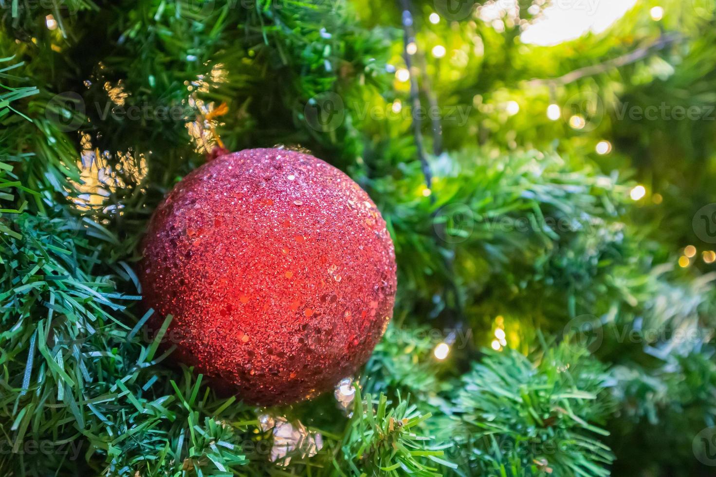 Christmas tree decorated with red ball on pine branches background photo