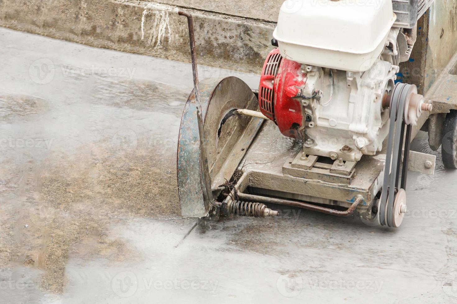 Worker using diamond saw blade machine cutting concrete road at construction site photo