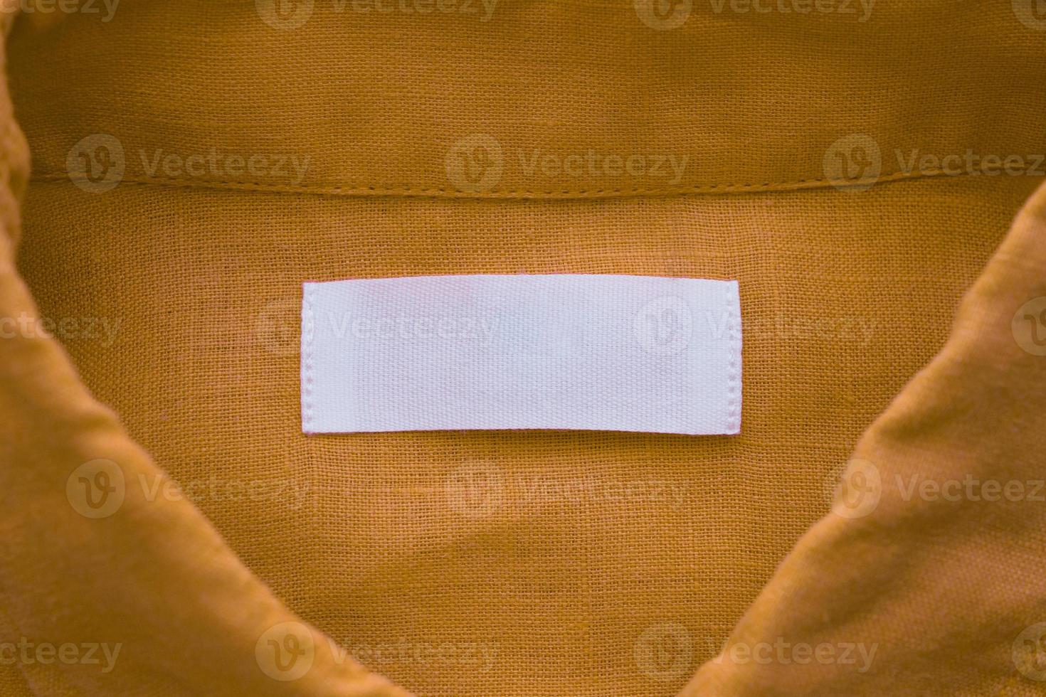 White blank clothing tag label on brown linen shirt fabric texture background photo