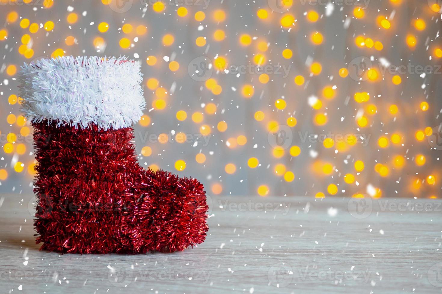 Red Santa's boot on wood table with bokeh light background photo