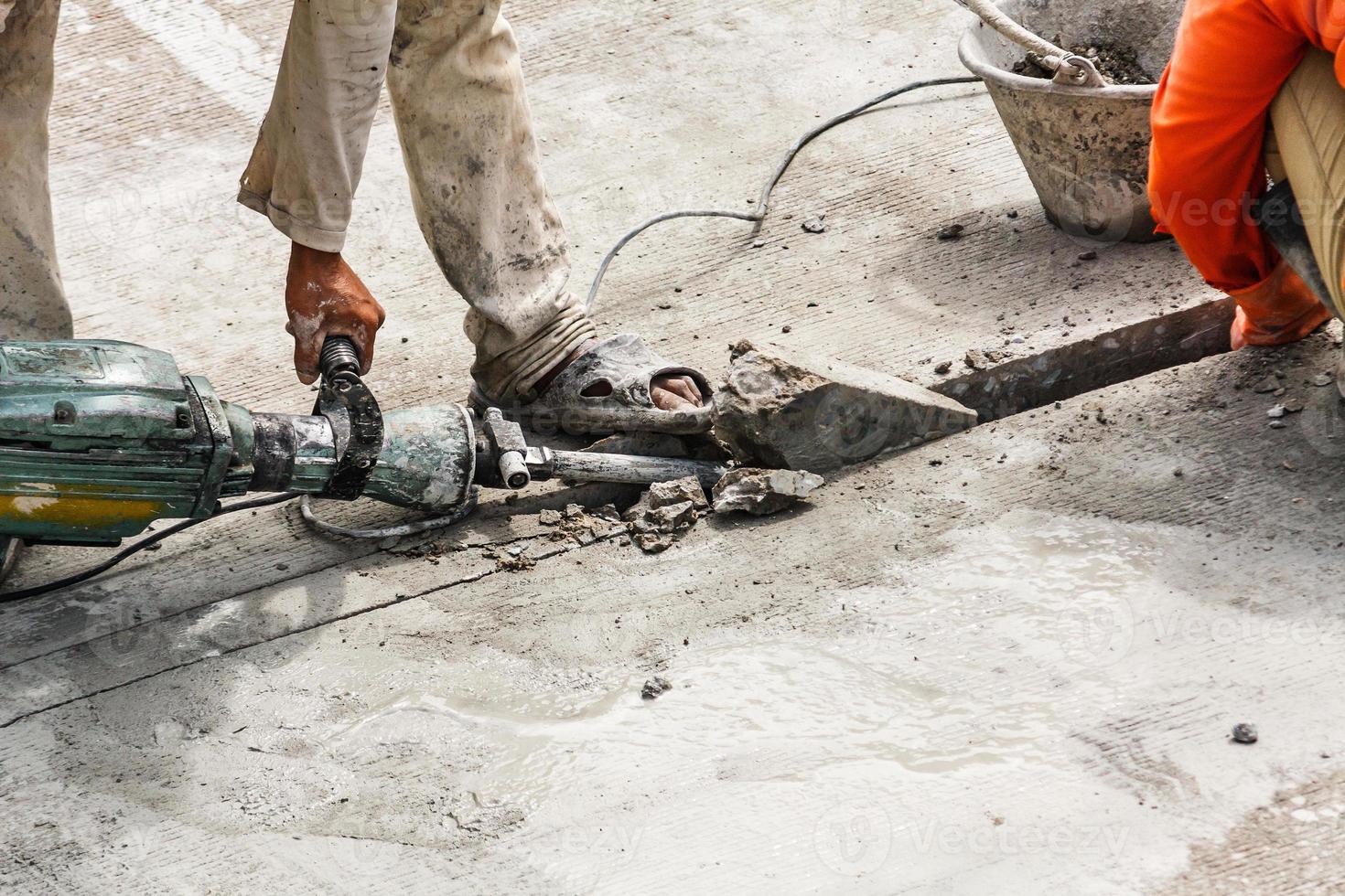 Construction worker using jackhammer drilling concrete surface photo