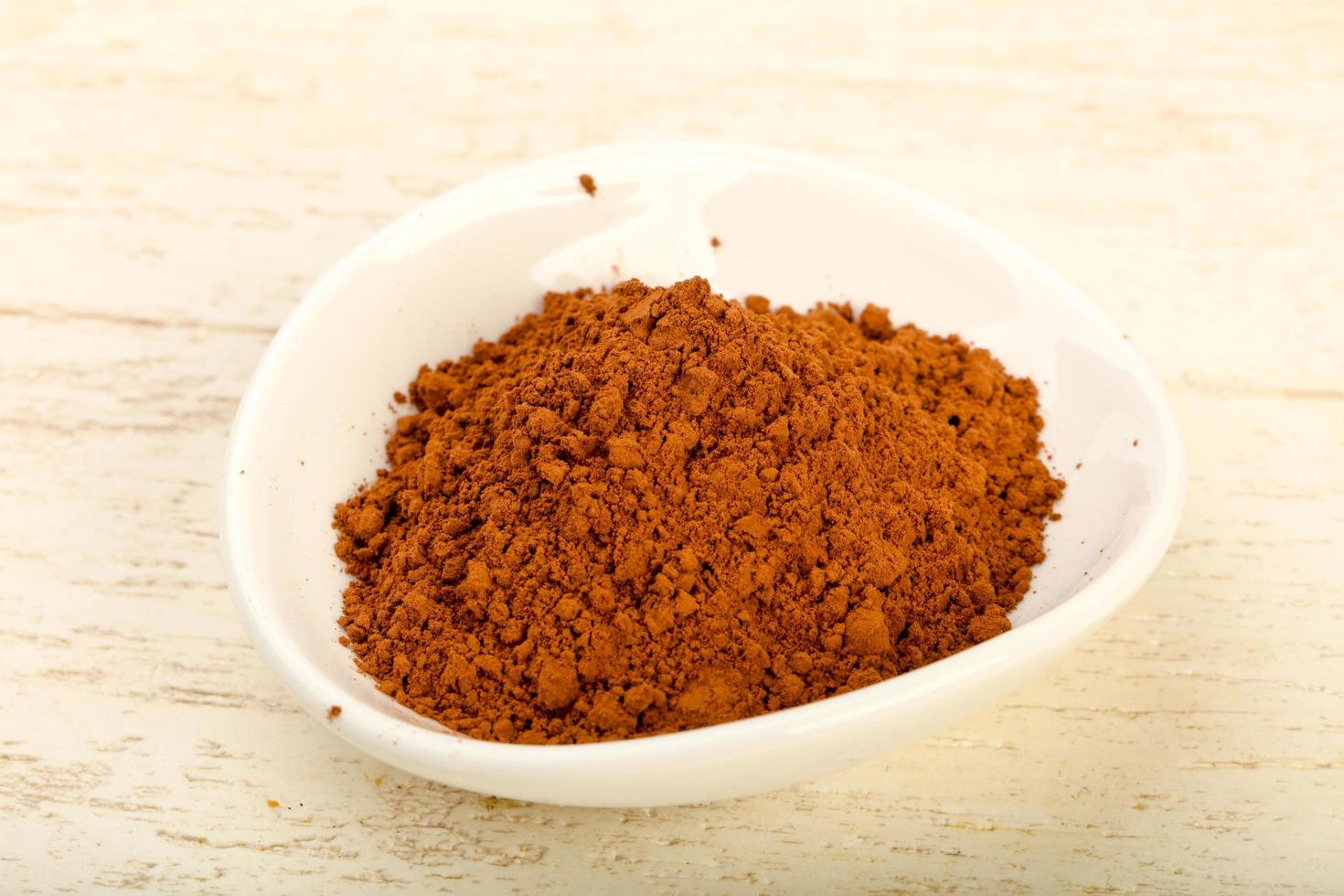 Cocoa powder in a bowl on wooden background photo
