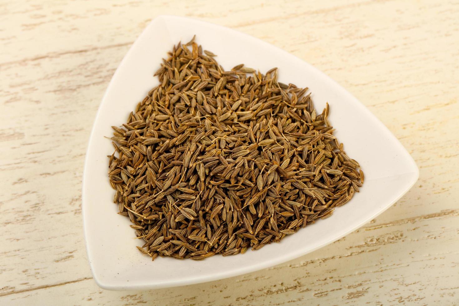 Cumin seeds in a bowl on wooden background photo