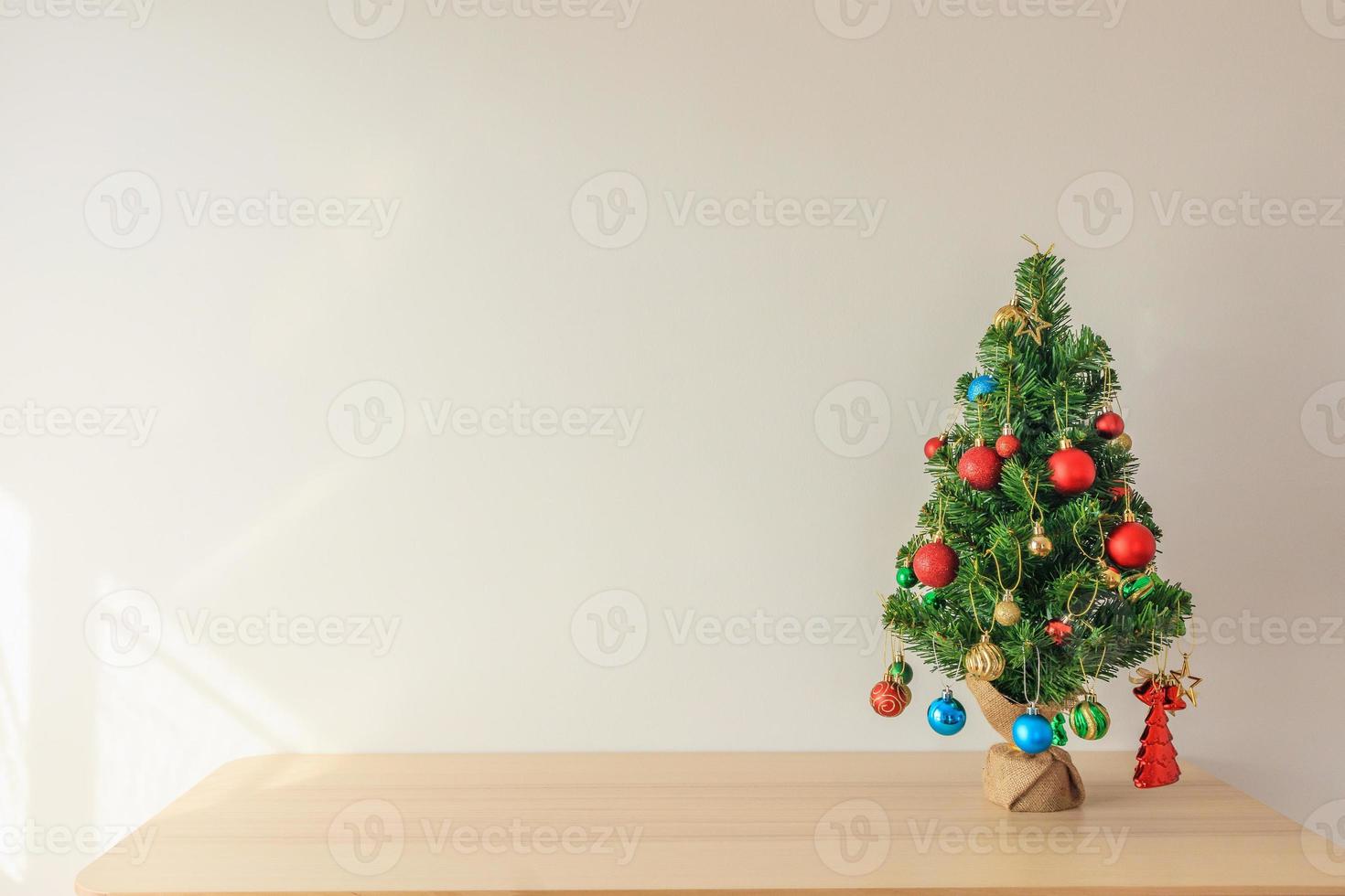 Christmas tree on wood table decorated with colorful ball on pine branches background photo