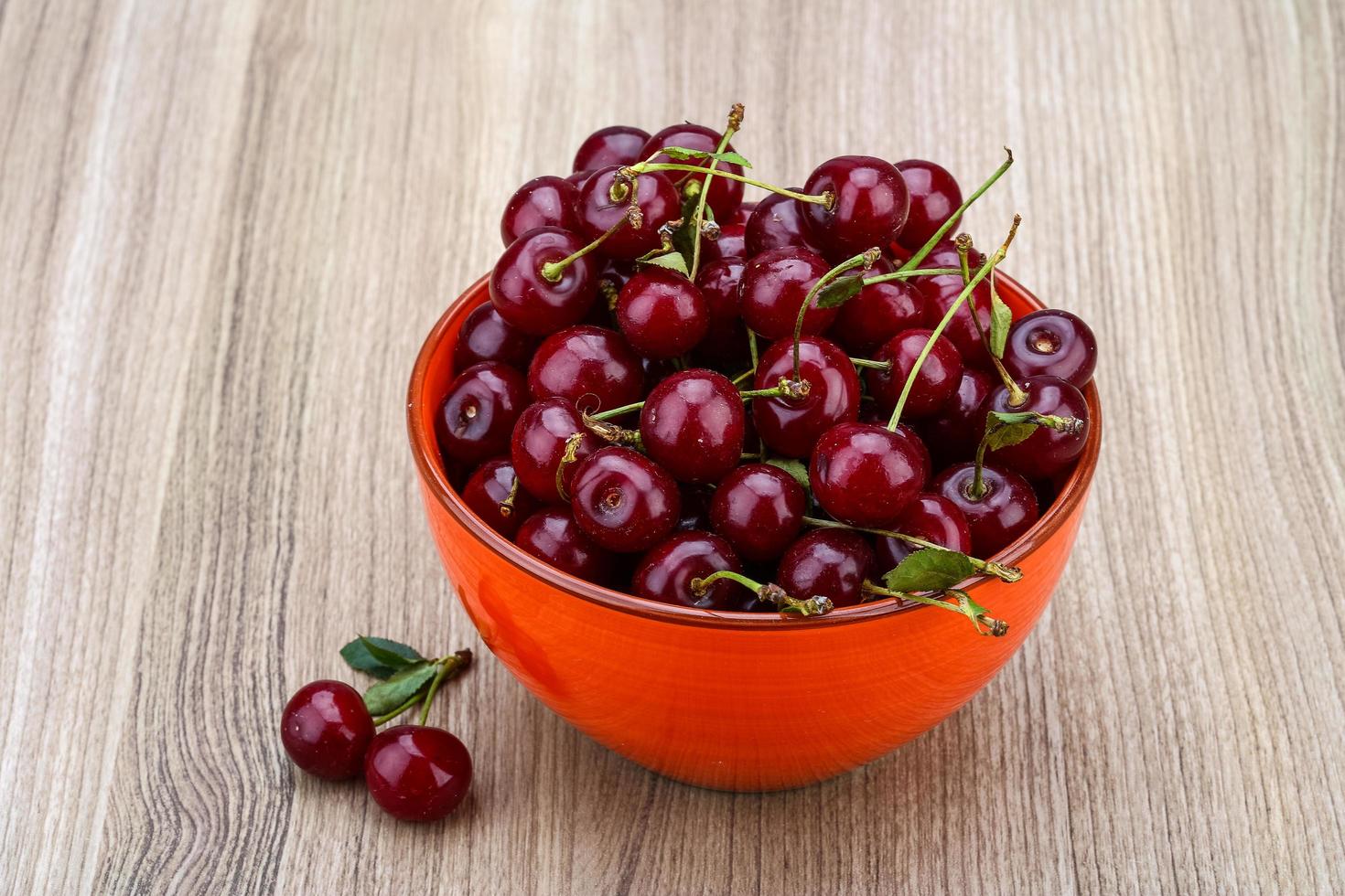 cereza en un recipiente sobre fondo de madera foto