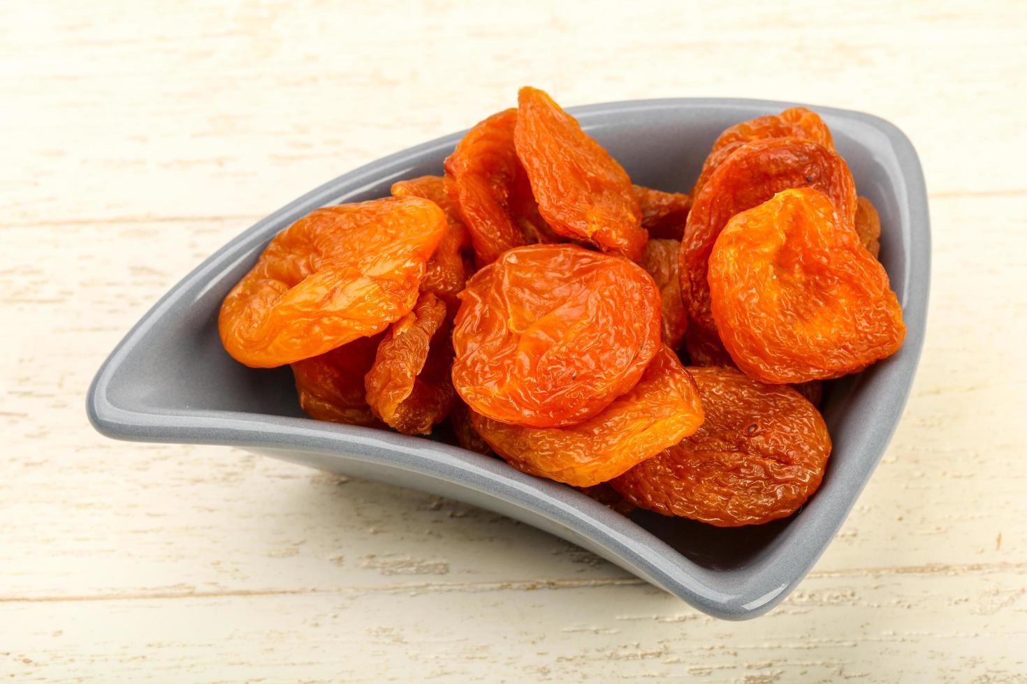 Dried apricots in a bowl on wooden background photo