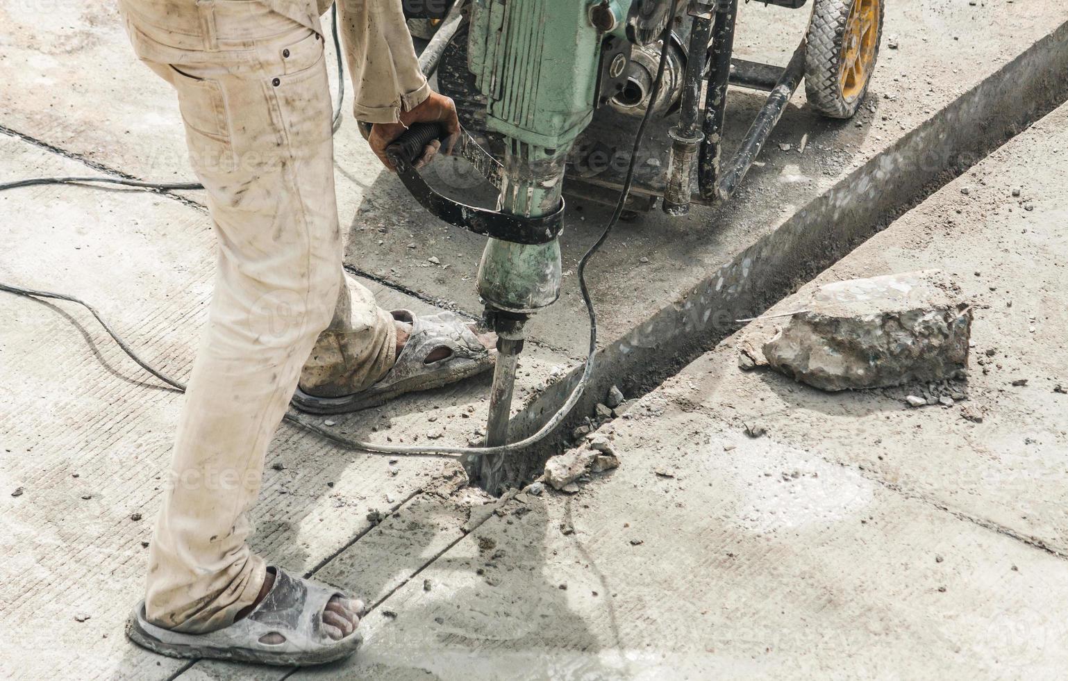 Construction worker using jackhammer drilling concrete surface photo