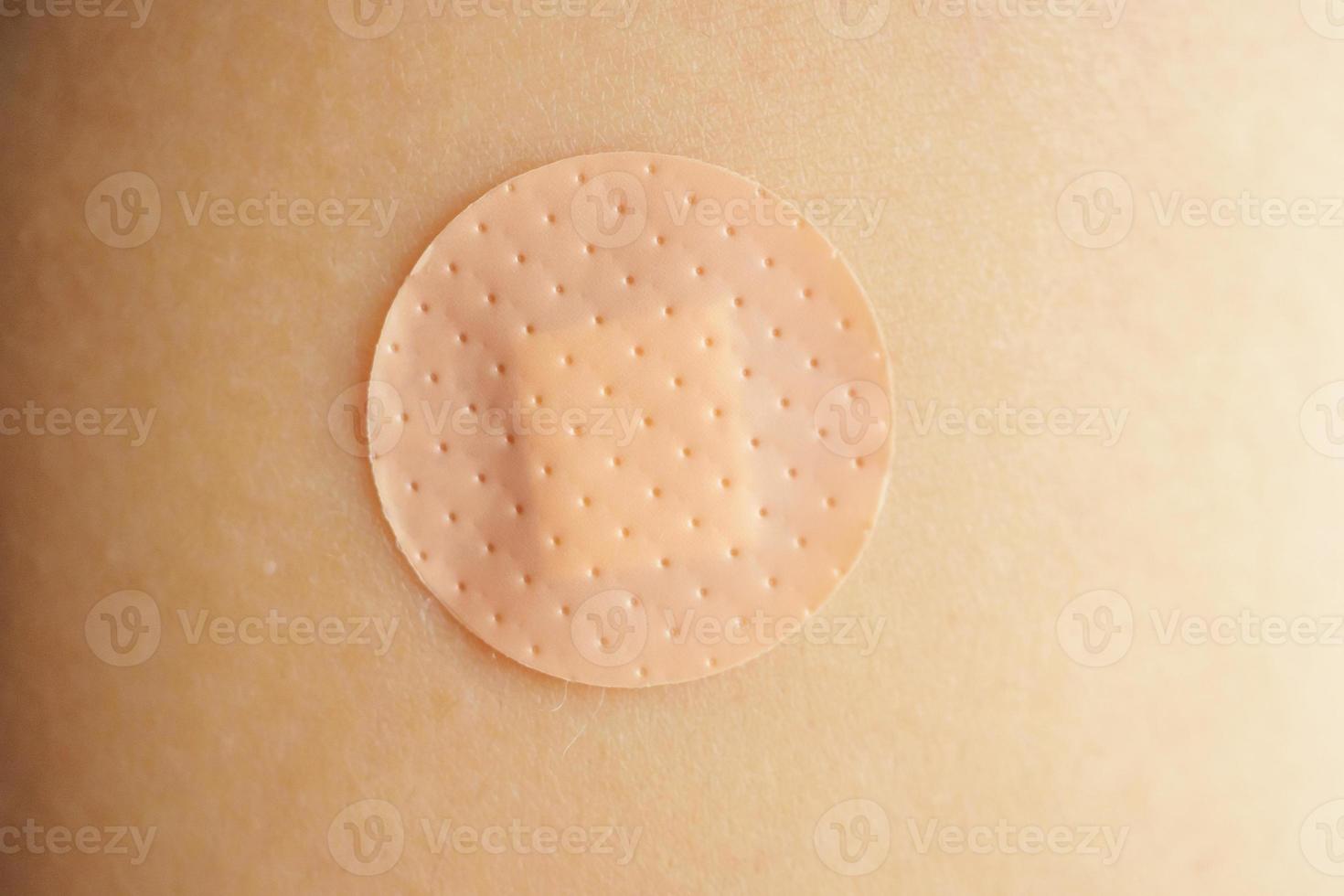 Close up circle brown adhesive bandage on patient arm after medicine injection or vaccination photo