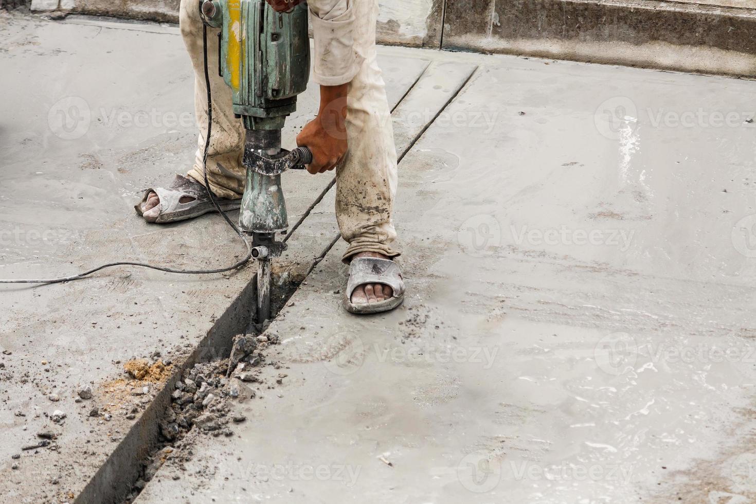 Construction worker using jackhammer drilling concrete surface photo